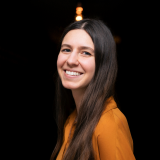 Agnes Maria Conrad Agnes im orangenen Oberteil mit schwarzem Hintergrund