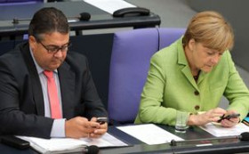 Sigmar Gabriel neben Angela Merkel, beide in ihr Handy tippend